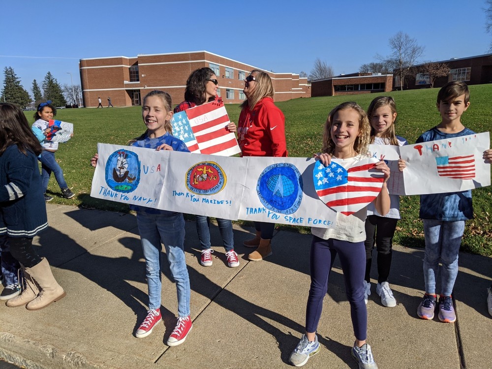 young students hold up homemade signs for veterans day